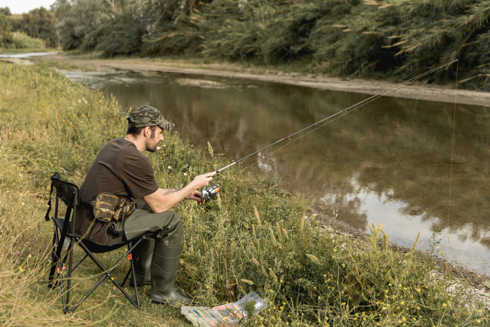 Man doing fishing sitting on river bank 