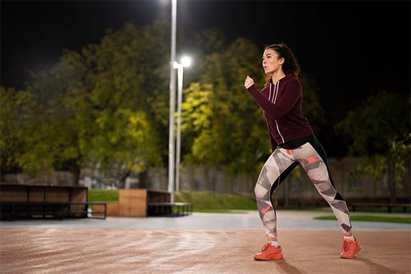 Woman running at night wearing running gear  