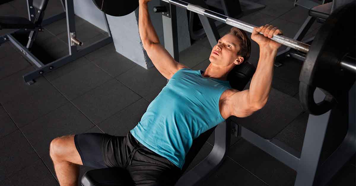 Boy doing bench press in gym
