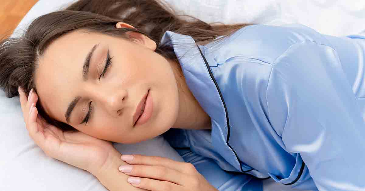 beautiful woman in blue pajamas laying on bed