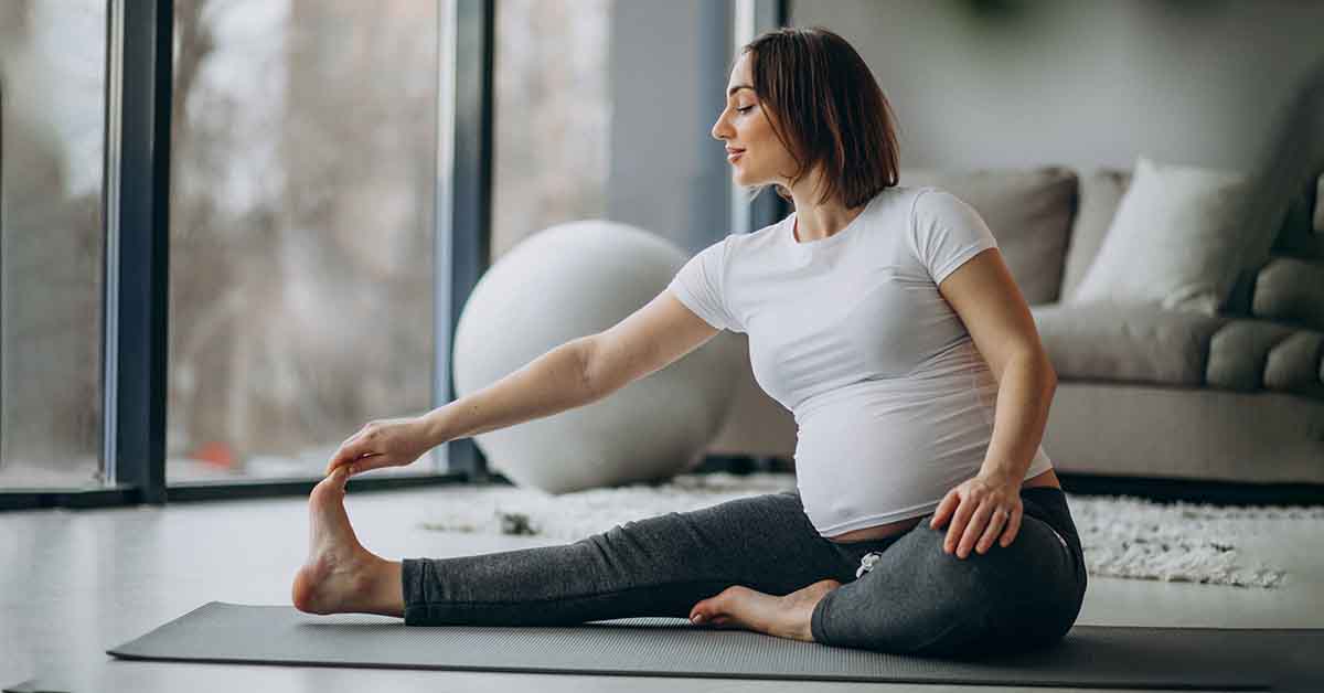 Young pregnant woman practicing yoga at home