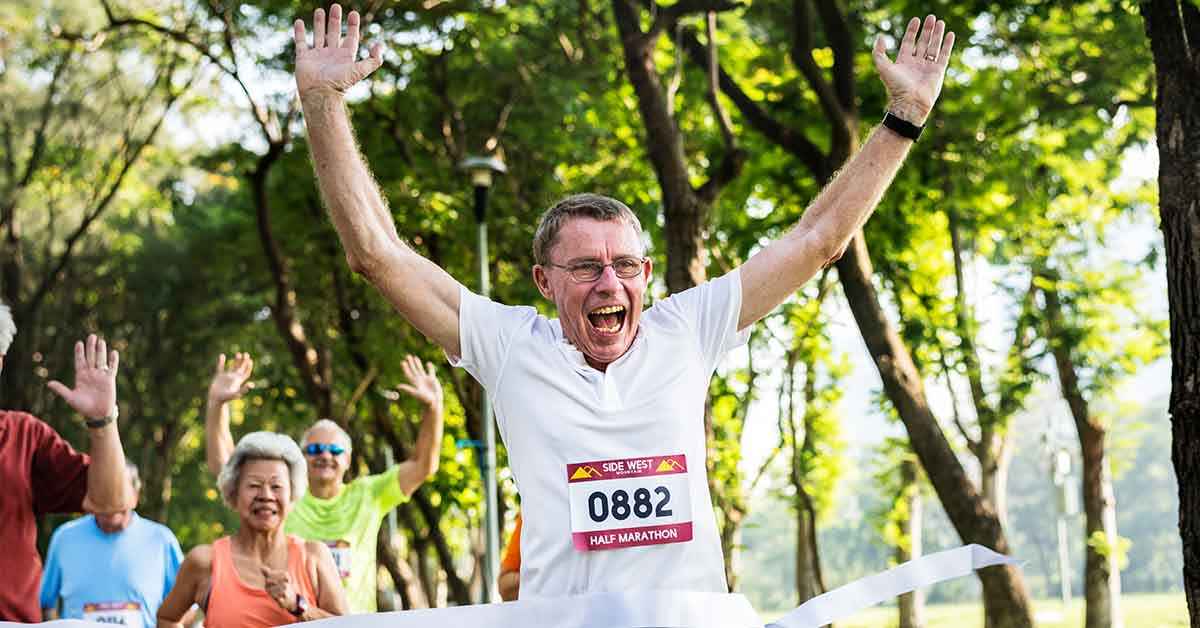 senior marathon running through the finish line