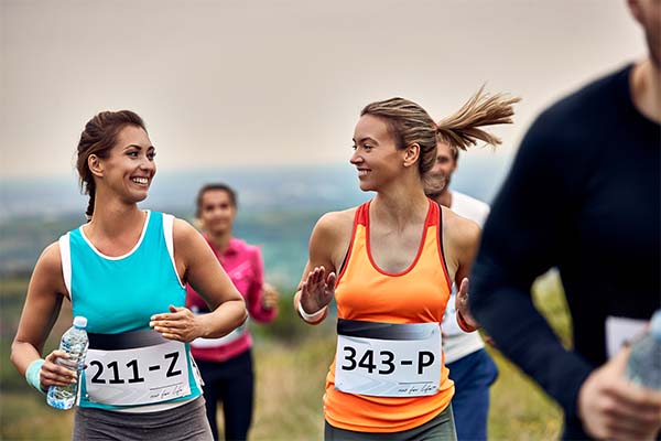 Young happy sportswomen participating in a marathon and communicating during the race