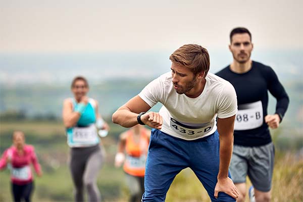 man checking his heart rate on smart watch after running marathon in nature