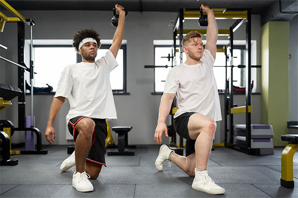 men training with kettlebell on mat