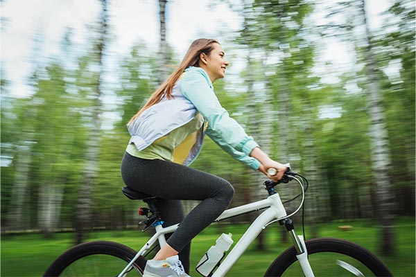 Happy girl cyclist riding on a mountain bike outside. Adventure travel.