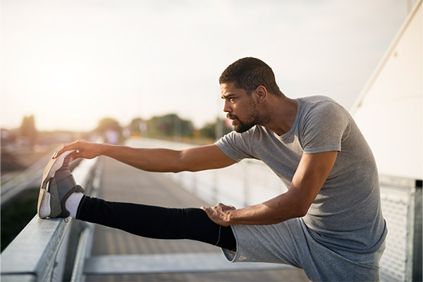 A male runner stretching his legs as part of his post workout recovery routine.