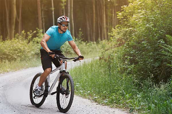 Man riding a mountain bike on a forest trail for outdoor fitness.