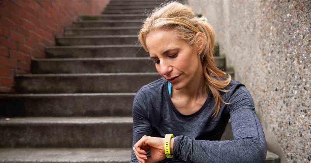 fit woman outdoors checking activity tracker