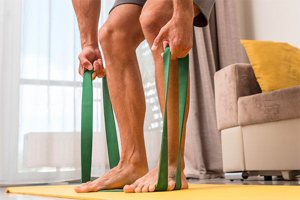 A man working out at home using an elastic band