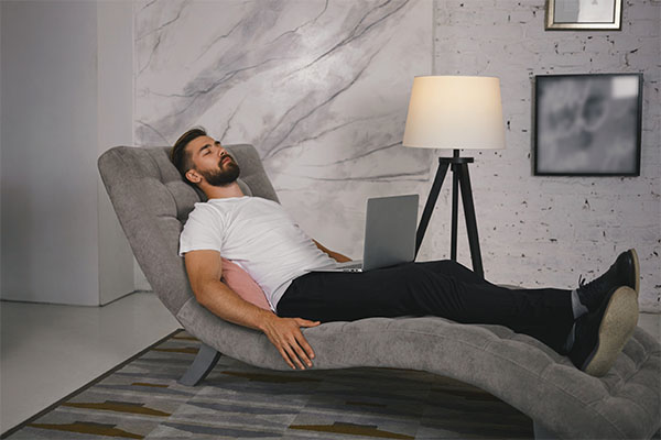 A man relaxing on a recliner with a laptop on his lap, enjoying some downtime at home. Rest During the Festive Season